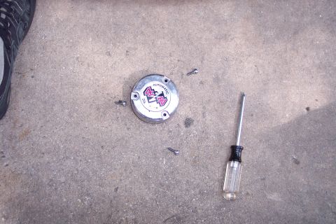 1996 Ford Bronco - A 4x4 automatic hub is shown with screws and a screwdriver on a concrete surface.