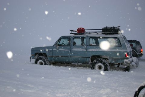 2003 Jeep TJ - Two SUVs are stuck in the snow, one with a roof rack and gas can is partially buried.