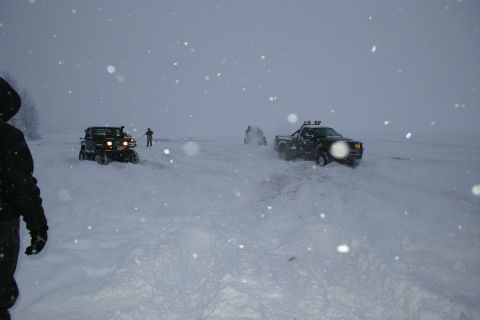 2003 Jeep TJ - Two vehicles navigate a snow-covered terrain under a cloudy sky with falling snow.