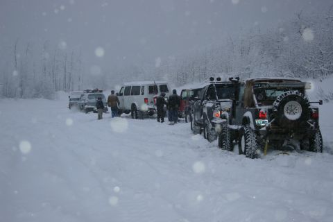 2003 Jeep TJ - A convoy of vehicles navigates a snowy trail, with several appearing to be stuck in the deep snow.