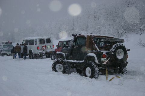 2003 Jeep TJ - Multiple off-road vehicles, including a Jeep TJ, are stuck in deep snow during a winter outing.
