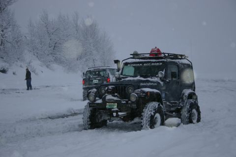 2003 Jeep TJ - Two off-road vehicles navigate a snowy landscape during a winter storm.