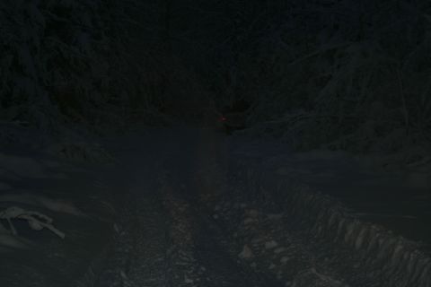 2003 Jeep TJ - A dark, snowy path winds through a forest at night, with a faint red light in the distance.