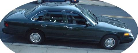 1997 Ford Crown Victoria - A dark green 1997 Ford Crown Victoria is parked curbside, showing its front passenger side profile.