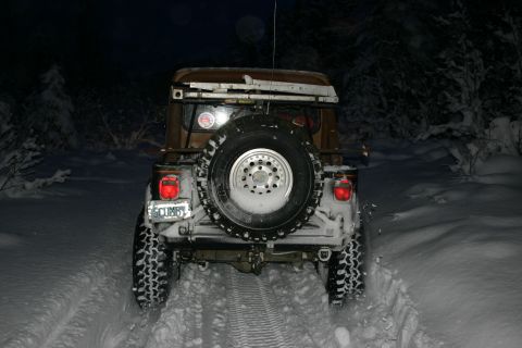 2003 Jeep TJ - A Jeep Wrangler TJ navigates a snowy path at night, its rear lights illuminating the tracks.