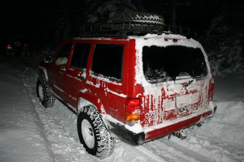 2003 Jeep TJ - Red Jeep Cherokee XJ in snow, with another vehicle in the background.