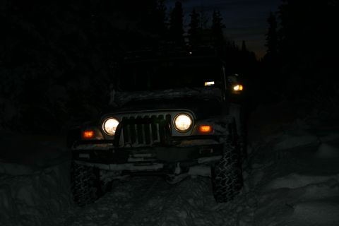 2003 Jeep TJ - A Jeep Wrangler navigates a snowy path in the dark, with another vehicle following closely behind.