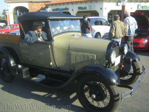 1985 Ford Mustang - A 1929 Ford Model A pickup truck is seen at a car show, with other vehicles in the background.
