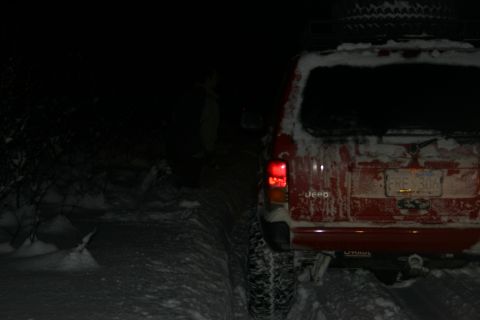 2003 Jeep TJ - Red 2003 Jeep TJ covered in snow, parked on a snowy trail at night.