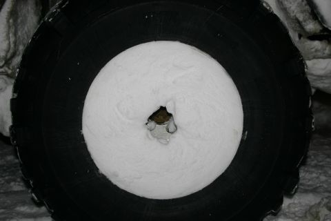 2003 Jeep TJ - A tire, heavily covered in snow, is visible with a dark hole in the center where ice has formed.