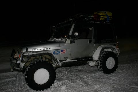 2003 Jeep TJ - A silver Jeep Wrangler Rubicon is parked in the snow at night, equipped with a roof rack.