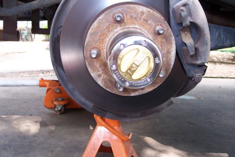 1996 Ford Bronco - A vehicle's wheel hub assembly, including the brake rotor and caliper, is shown on a jack stand.