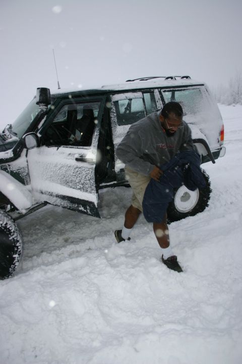 2003 Jeep TJ - A man exits a snow-covered Jeep Cherokee XJ in a snowy landscape.