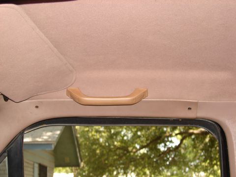 1996 Ford Bronco - A tan grab handle is mounted on the interior ceiling of a vehicle.