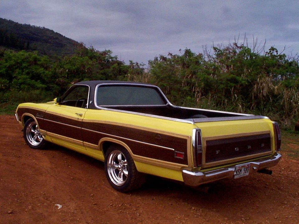 Yellow Ford Ranchero with woodgrain trim, rear view on dirt road