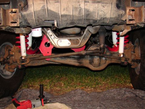 1996 Ford Bronco - The underside of a vehicle shows suspension components and a differential, with tools nearby.