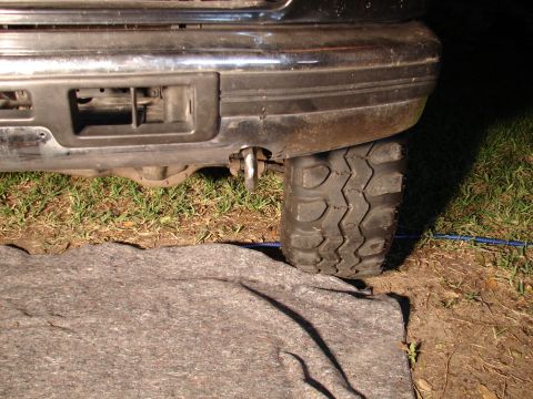 1996 Ford Bronco - Close-up view of a tow hook mounted on the rear bumper, next to a large off-road tire.