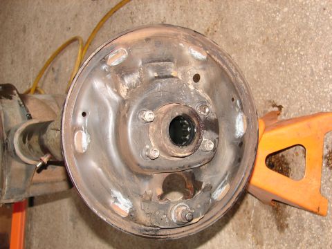 1996 Ford Bronco - Close-up of a vehicle's brake drum assembly, resting on an orange jack stand.