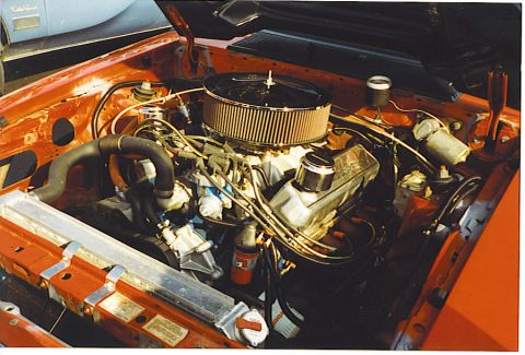 1992 Ford Mustang - The engine bay of a red Fox body Mustang is shown, its V8 engine and various components.