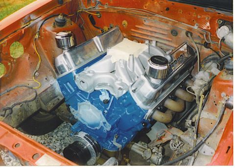 1992 Ford Mustang - Close-up view of a modified engine in an orange vehicle's engine bay, a blue block and chrome components.