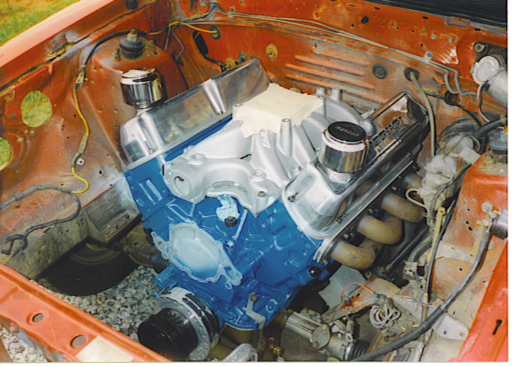 Engine bay with blue engine block, chrome valve covers, and exhaust headers