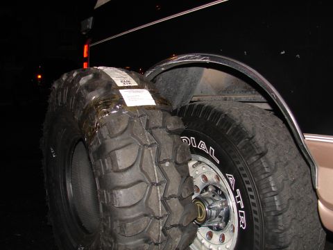 1996 Ford Bronco - A new, aggressive tread off-road tire is shown next to the vehicle's current tire and wheel assembly.