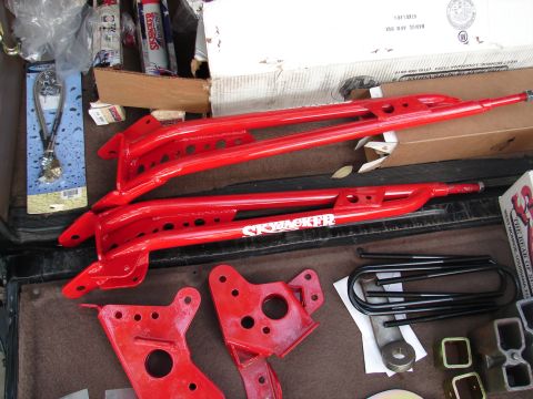 1996 Ford Bronco - Red suspension parts, including control arms and brackets, are laid out with hardware.