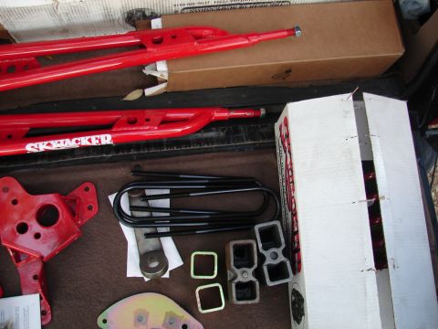 1996 Ford Bronco - Red Skyjacker suspension parts, including control arms and U-bolts, are laid out with hardware.