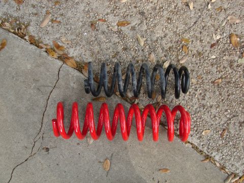 1996 Ford Bronco - Comparison of red and black coil springs on a concrete surface.