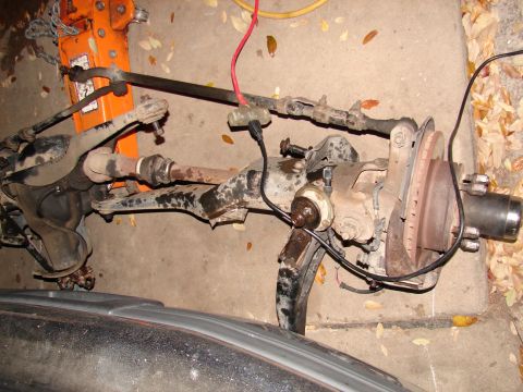 1996 Ford Bronco - A disassembled front suspension assembly rests on the ground, supported by an orange jack.