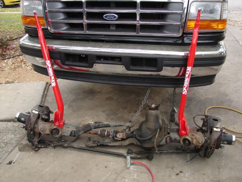 1996 Ford Bronco - The front axle assembly of a Ford truck is shown removed from the vehicle, with suspension components attached.