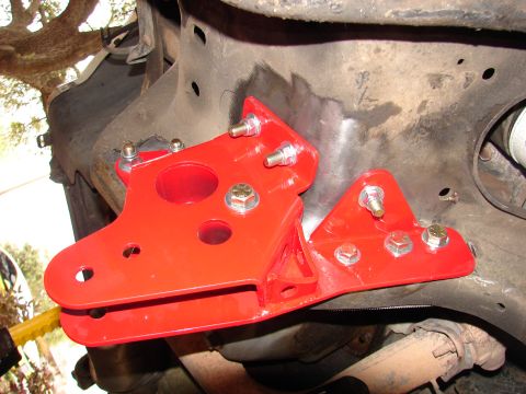 1996 Ford Bronco - Close-up view of a red metal bracket installed on a vehicle's frame, likely for suspension modification.