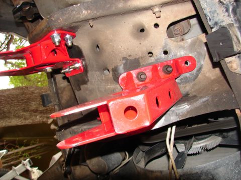 1996 Ford Bronco - Close-up view of red lift kit components installed on a vehicle's frame, highlighting suspension modifications.