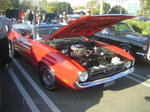 1985 Ford Mustang - A red convertible Mustang from the 1970s is displayed with its hood open at a car show.