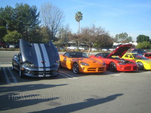 1985 Ford Mustang - Several sports cars, including a gray Dodge Viper, are parked in a lot on a sunny day.