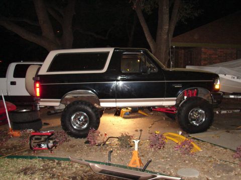 1996 Ford Bronco - Customized Ford Bronco with aftermarket suspension and tires, parked next to a pickup truck.