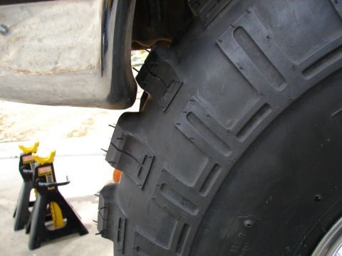 1996 Ford Bronco - A vehicle is supported by jack stands, showing a close-up view of its large tire and fender assembly.