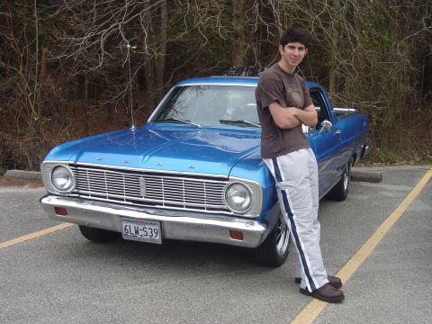 1966 Ford Ranchero - A man leans against a blue 1966 Ford Ranchero pickup truck in a parking lot.