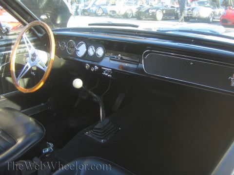 1985 Ford Mustang - Interior view of a classic Mustang, a wood-rimmed steering wheel and manual transmission shifter.