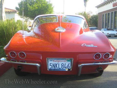 1985 Ford Mustang - Rear view of a red 1963 Chevrolet Corvette Sting Ray convertible at a car show.