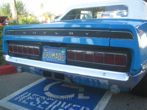 1985 Ford Mustang - Rear view of a blue Shelby convertible, parked in a reserved spot.
