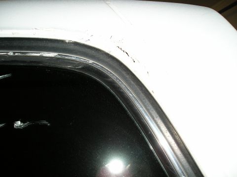1993 Ford Bronco - Close-up of a white vehicle's window frame and surrounding bodywork, revealing signs of wear and damage.