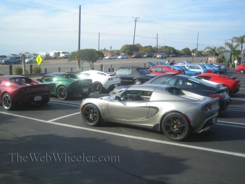 1985 Ford Mustang - A collection of Lotus Elise sports cars are parked in a lot under a bright sky.