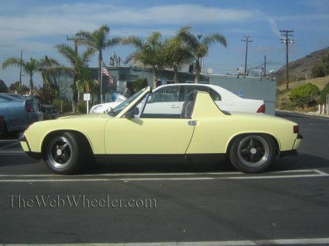 1985 Ford Mustang - Side view of a yellow Porsche 914 Targa in a parking lot.