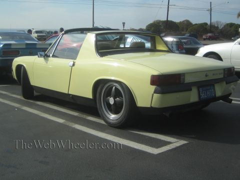 1985 Ford Mustang - A yellow Porsche 914 is parked in a lot, showing its rear end and a portion of the interior.