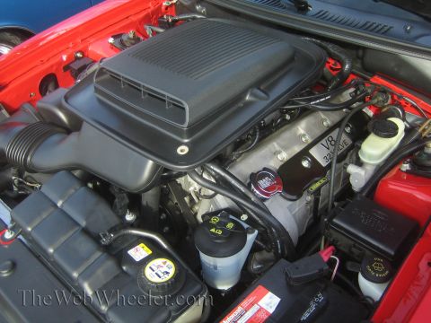 1985 Ford Mustang - Close-up view of a V8 32 valve engine in a red car, a prominent black air intake system.