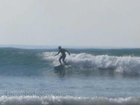 1985 Ford Mustang - A surfer catches a wave on a sunny day at the beach.