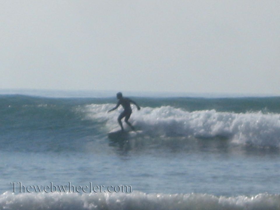 Surfer riding a wave with the ocean and sky in the background