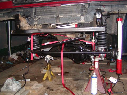 1991 Ford Bronco - The underside of a vehicle is shown with its suspension system and various tools.