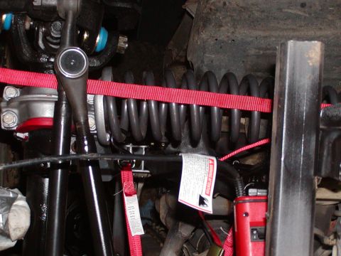 1991 Ford Bronco - The image shows a close-up view of a vehicle's suspension system, including a coil spring and various metal components.